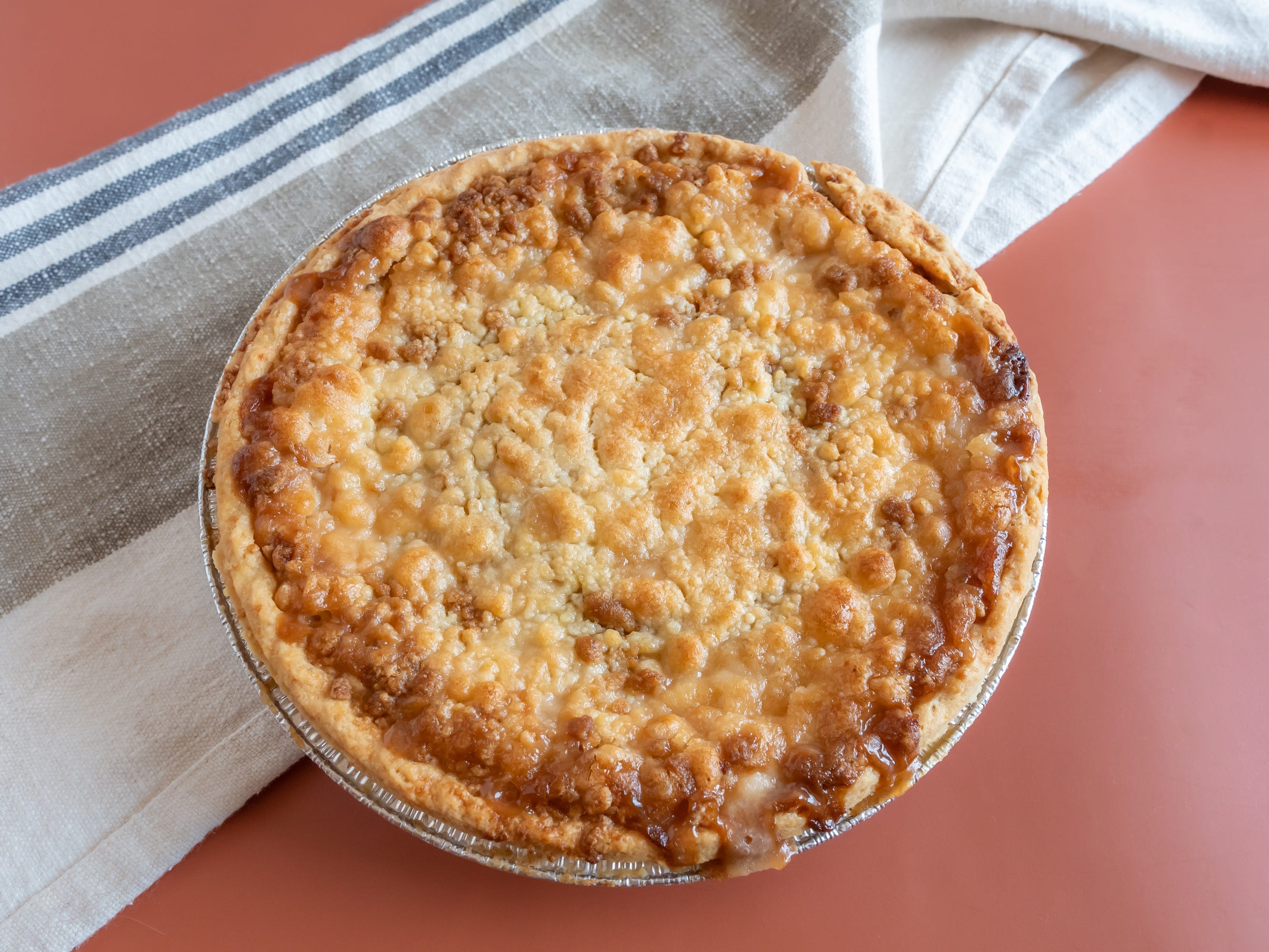 Whole baked apple pie from Kroger on red table