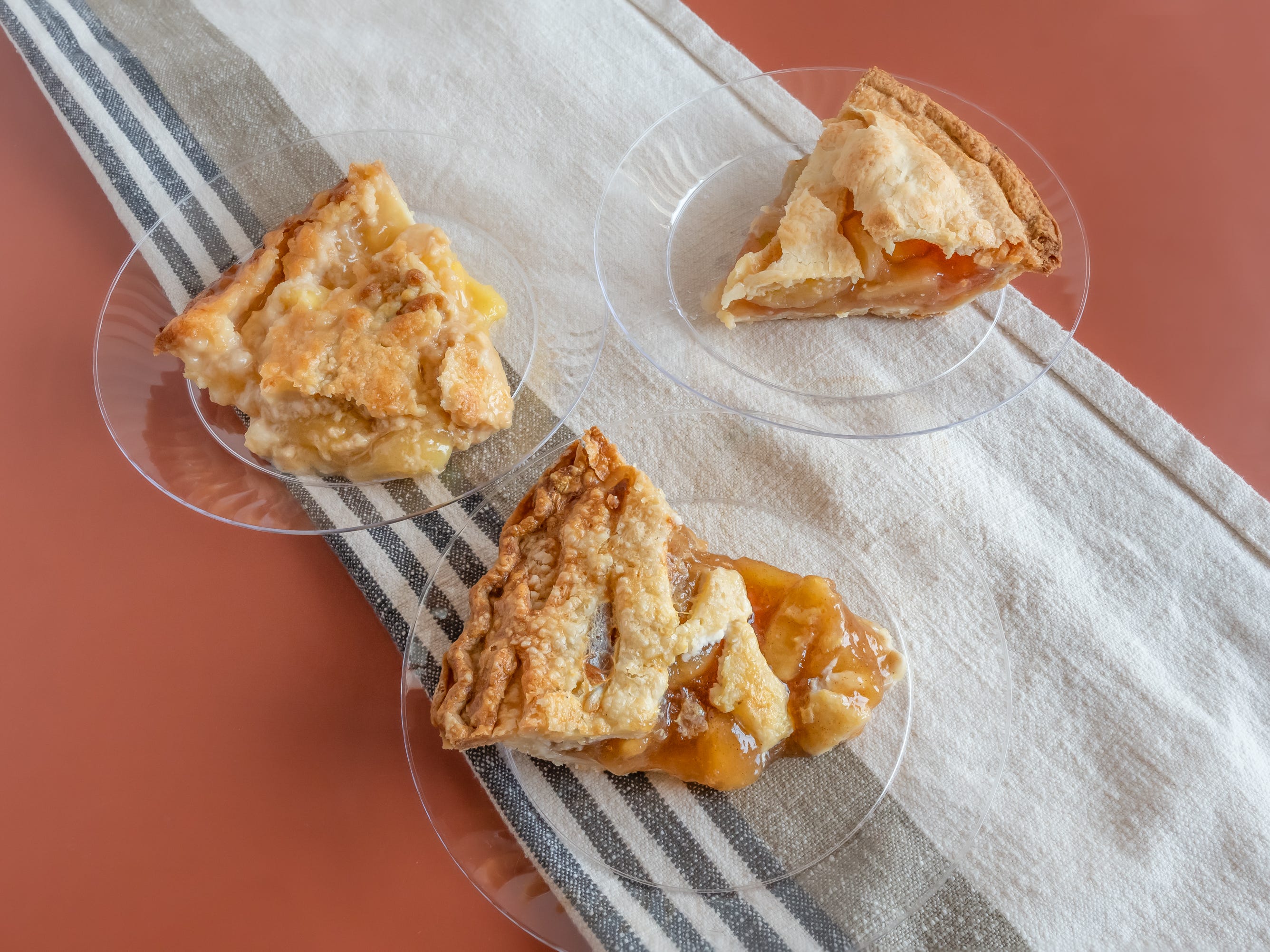 Slices of apple pies from whole foods, krogers, and safeway on red table