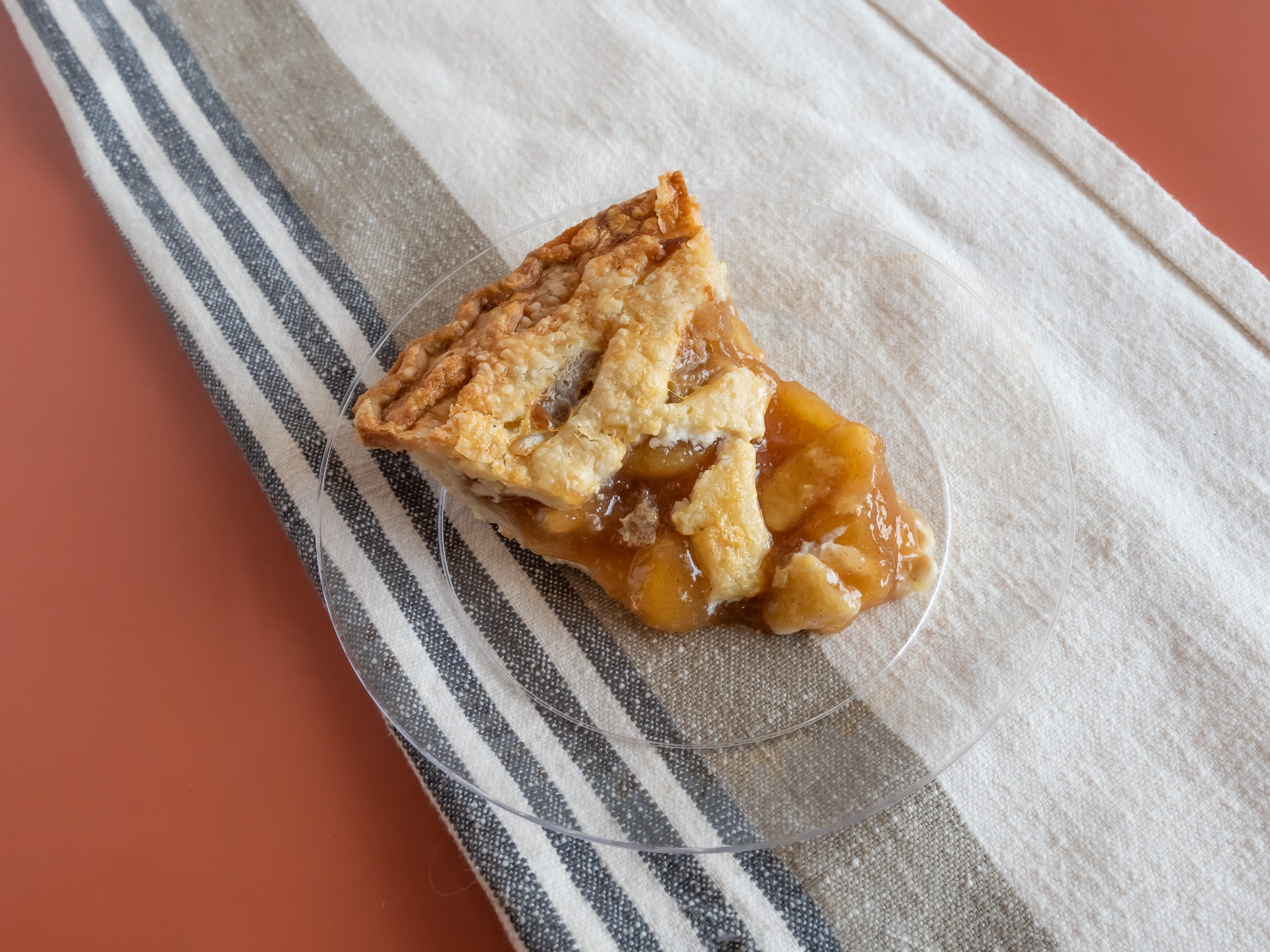 slice of safeway apple pie on small clear plate on red table