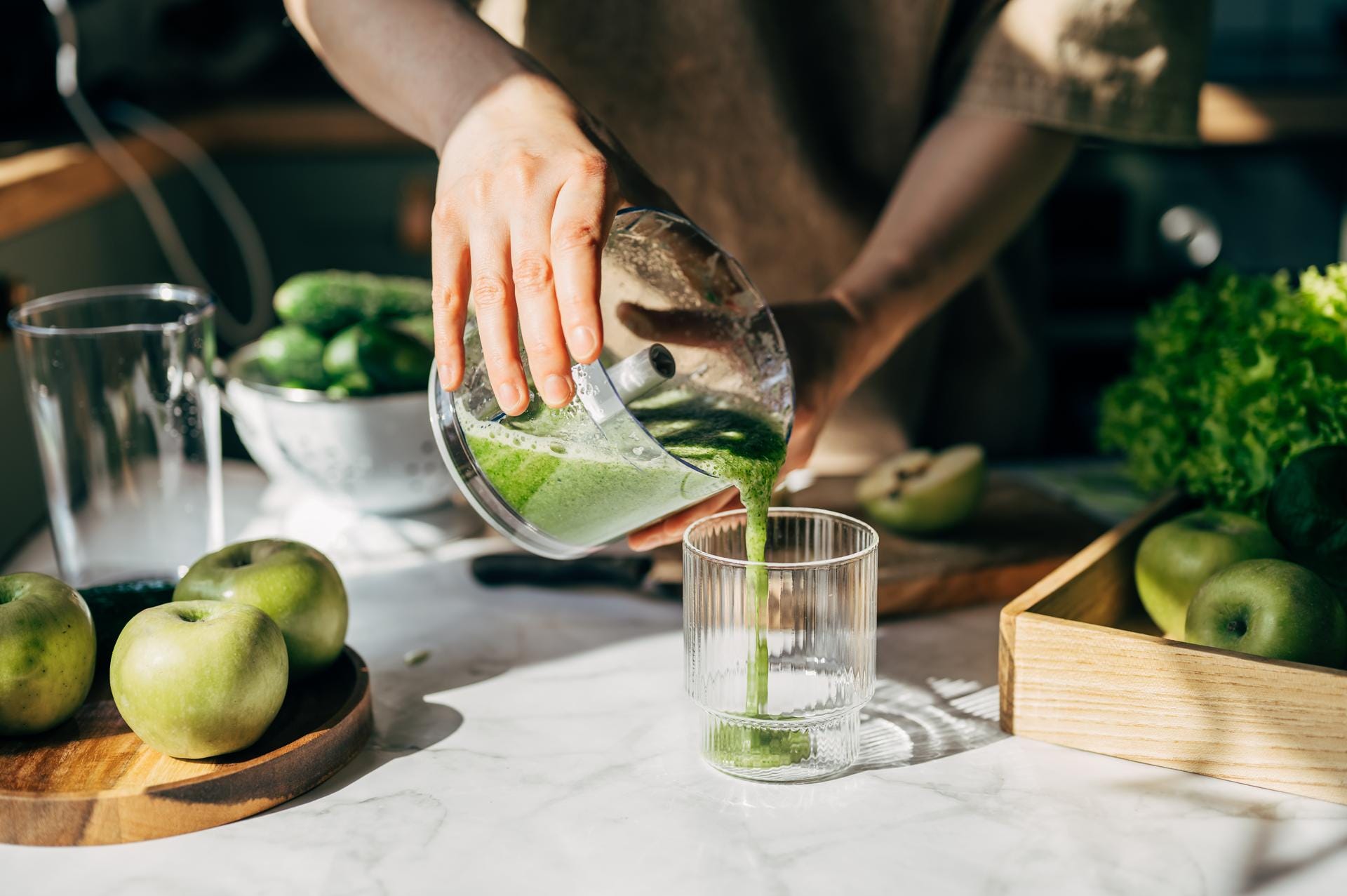 Person pouring green juice into glass