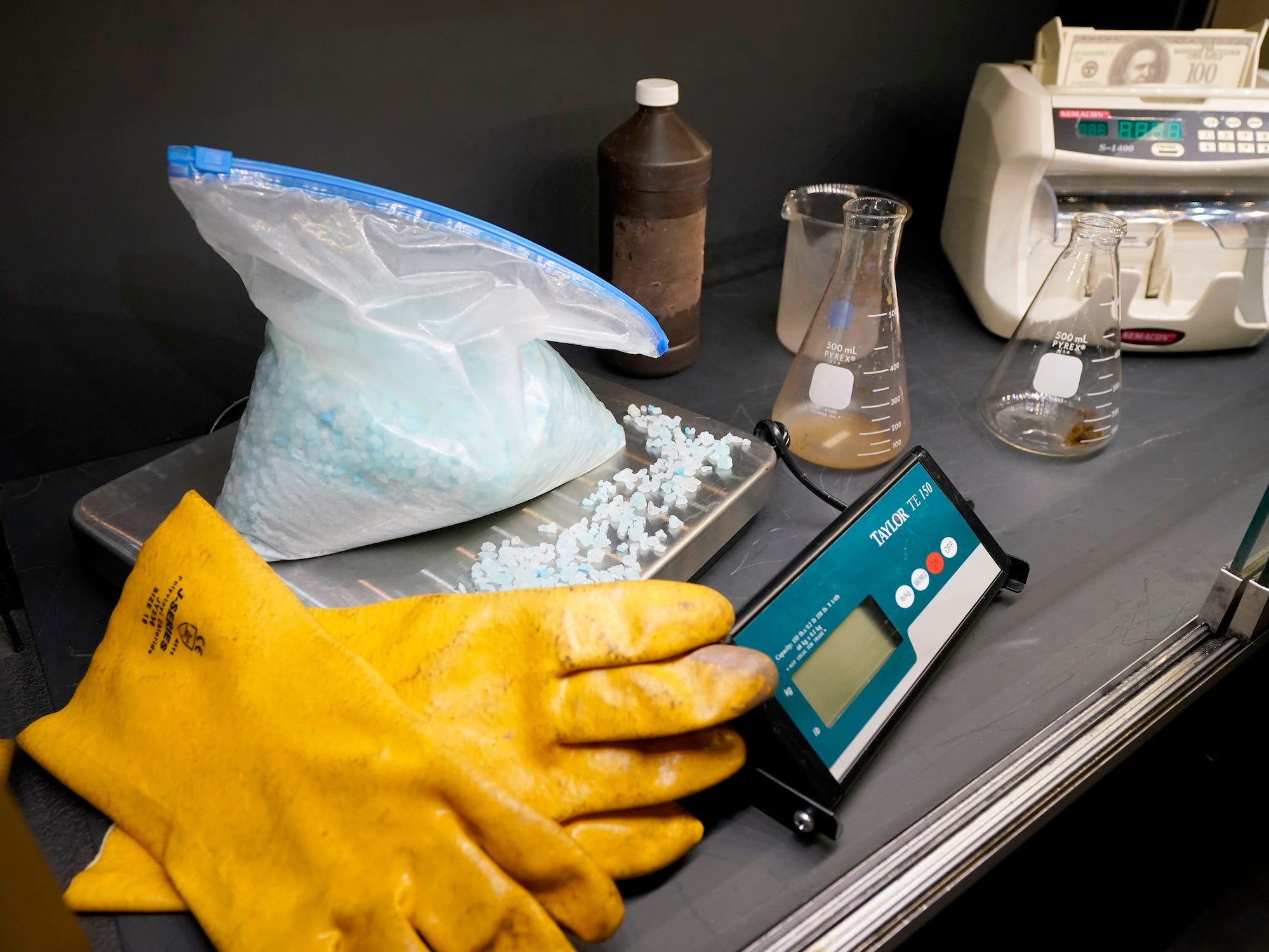 Yellow gloves, a scale with a plastic bag full of blue crystals, and other props from Breaking Bad