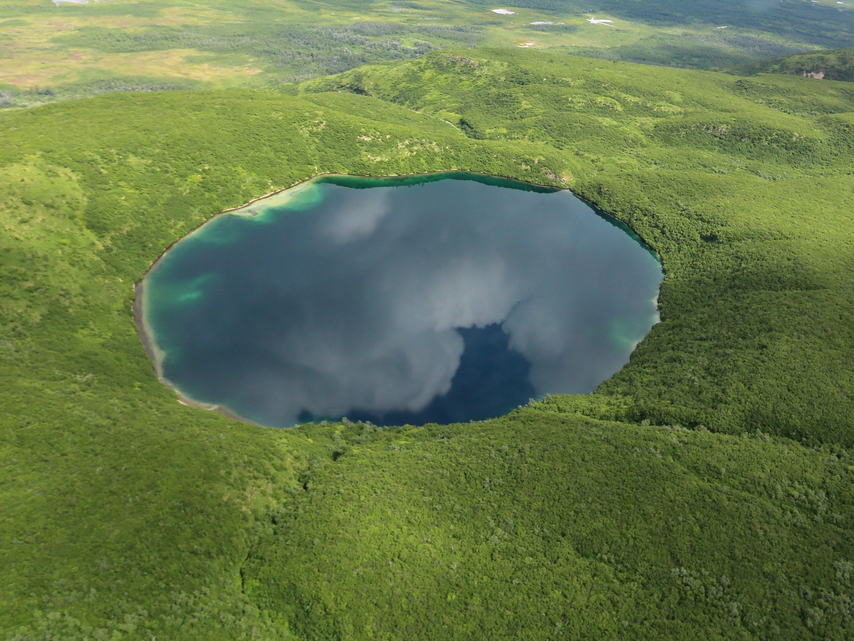 A blue lake that's very round surrounded by green