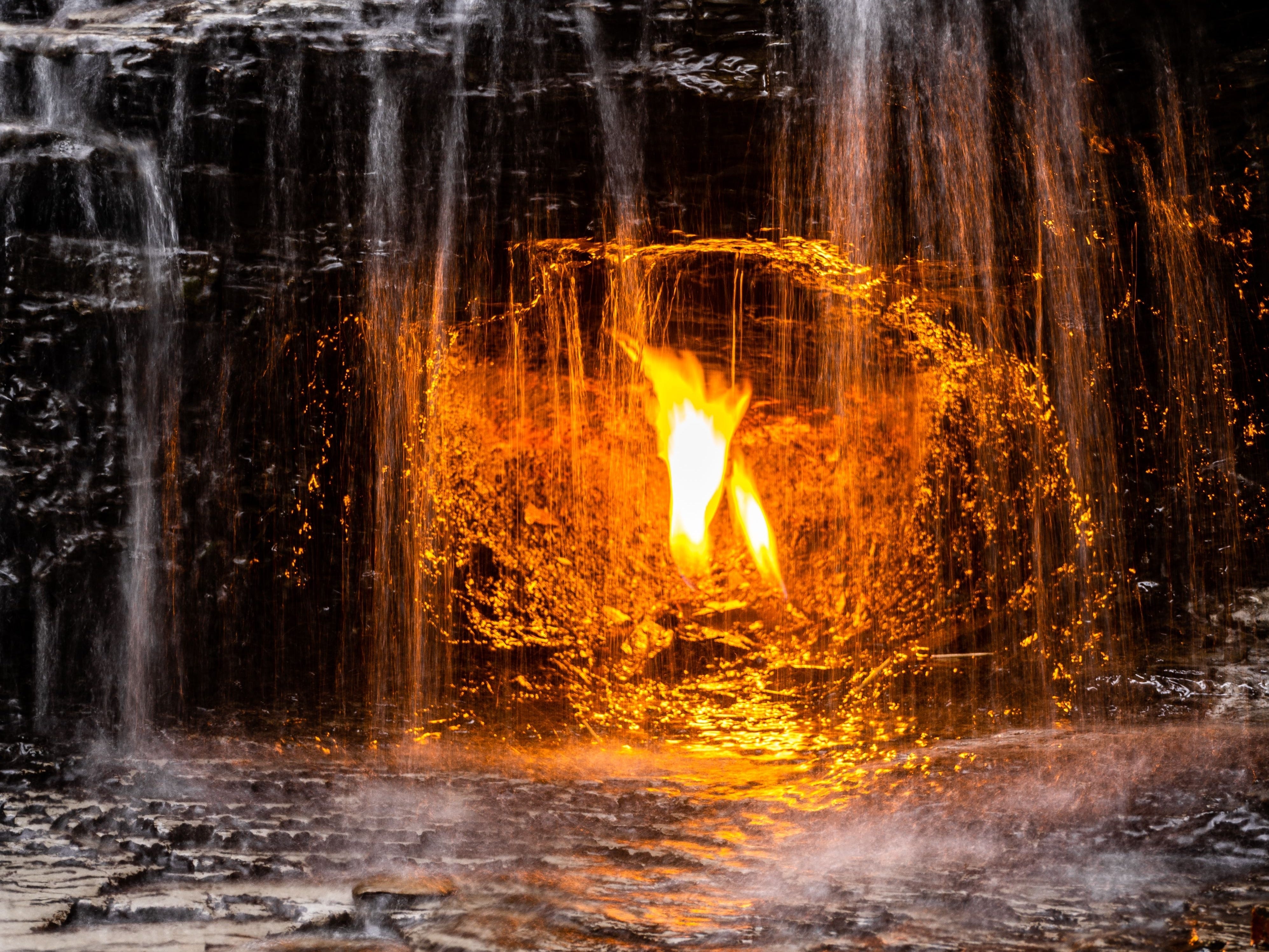 A flame glows in an alcove with water falling in front of it