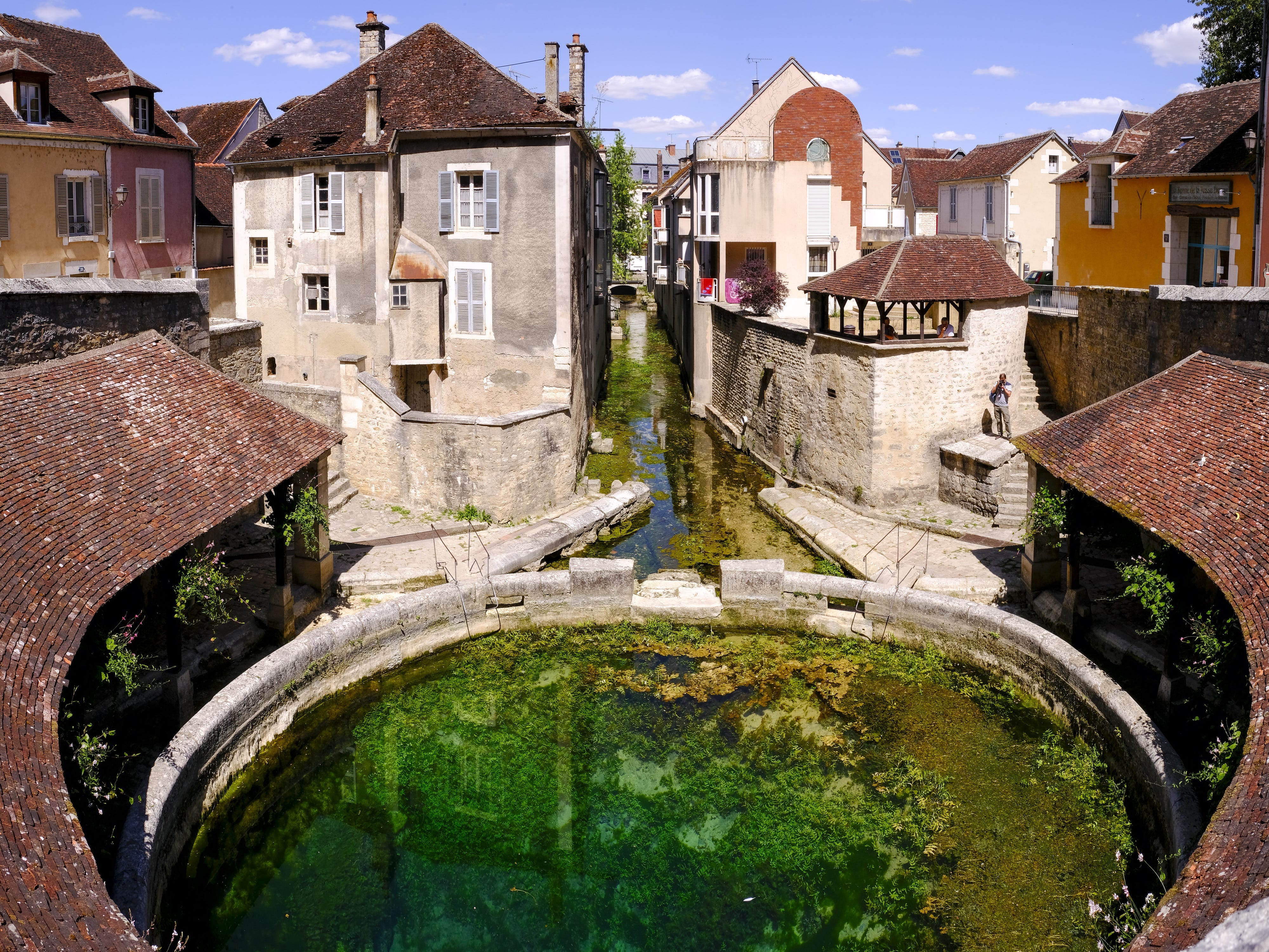 Buildings surround a pit filled with water that has stone walls surrounding
