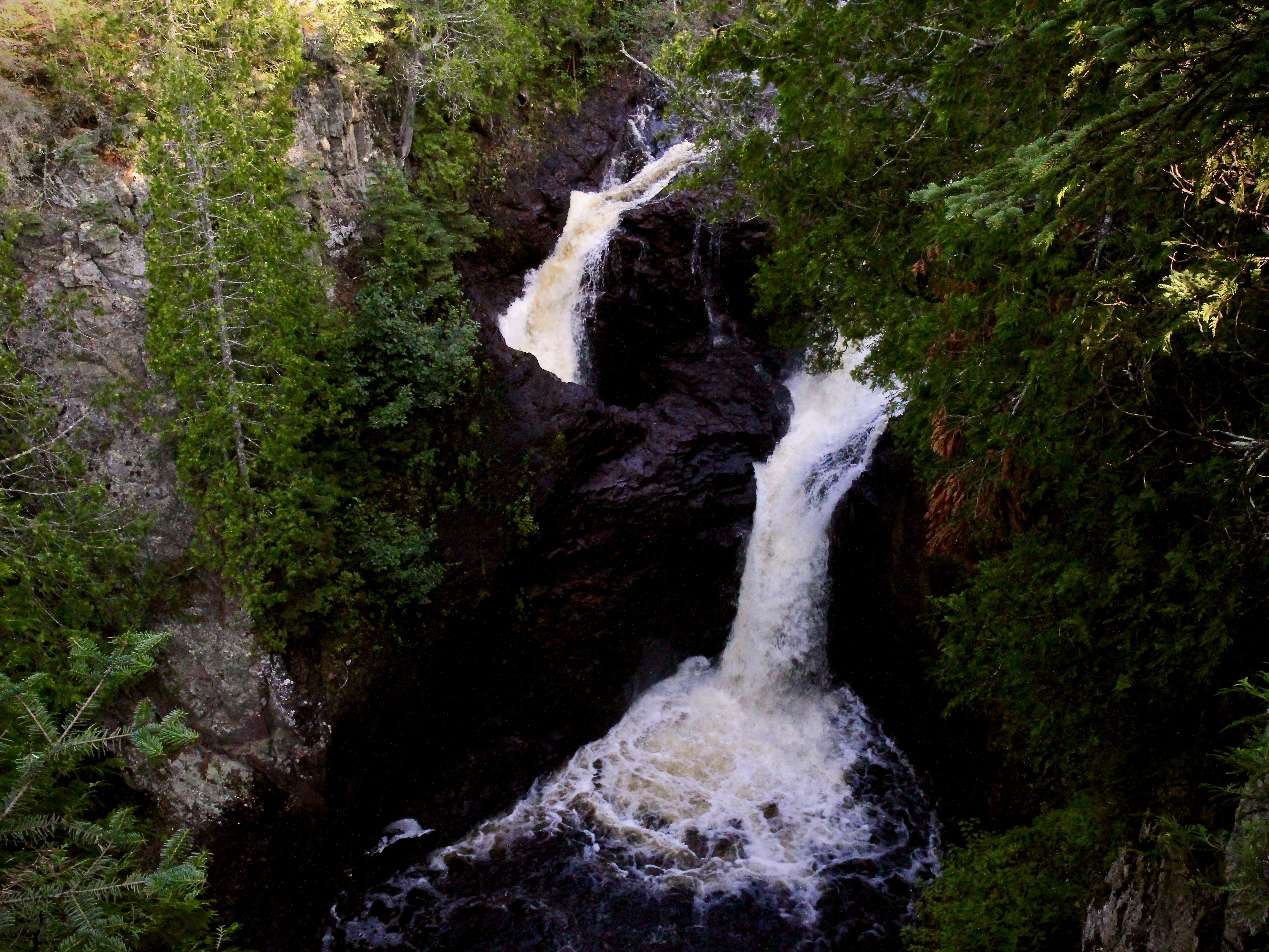 A waterfall with two parts, one dropping into a hole