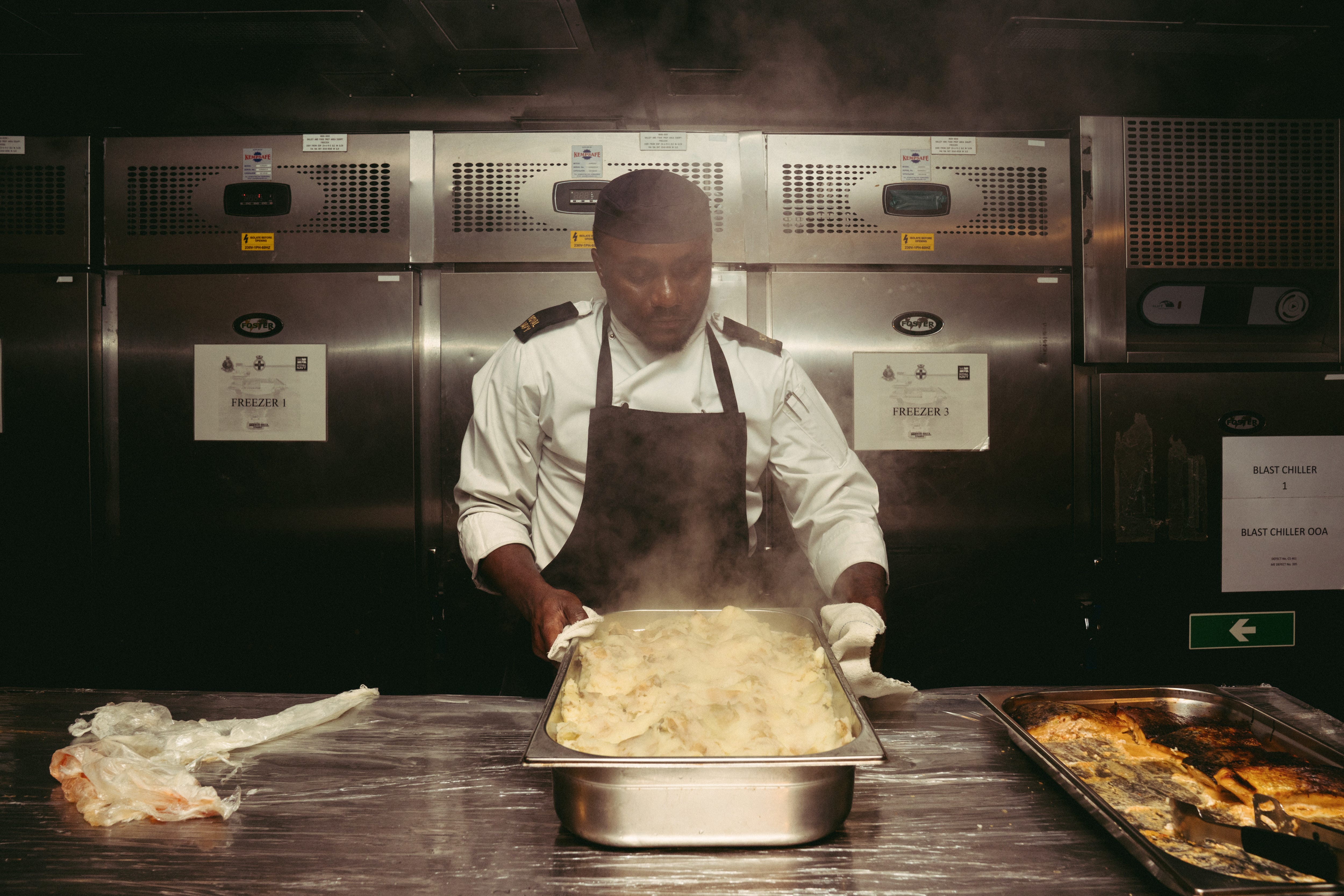 AB1 Ockheem "Hibby" holds a tray of steaming mashed potatoes.