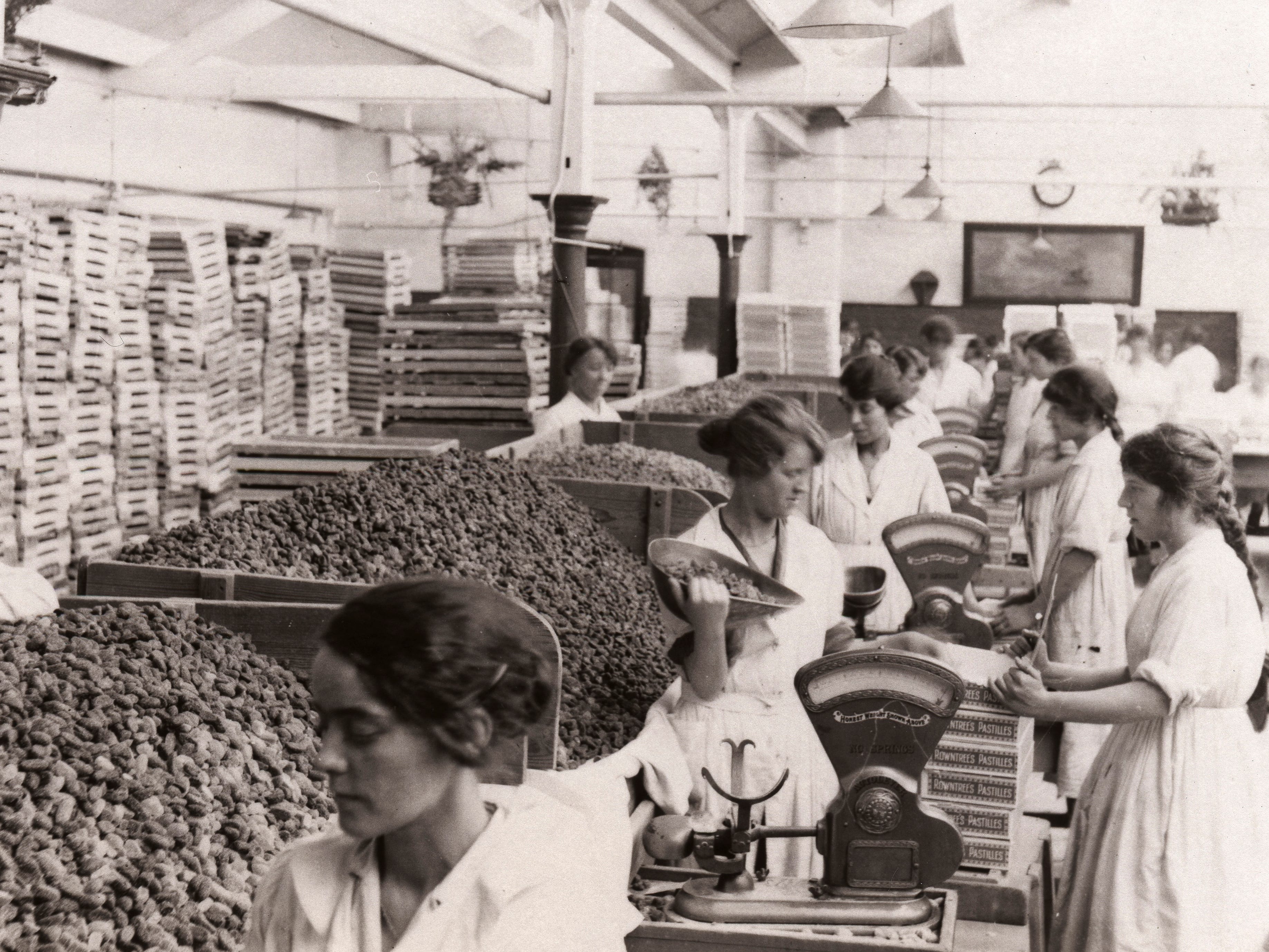Women in York, England, weighing and packing Rowntree Fruit Pastilles in 1923. They all wore white dresses.