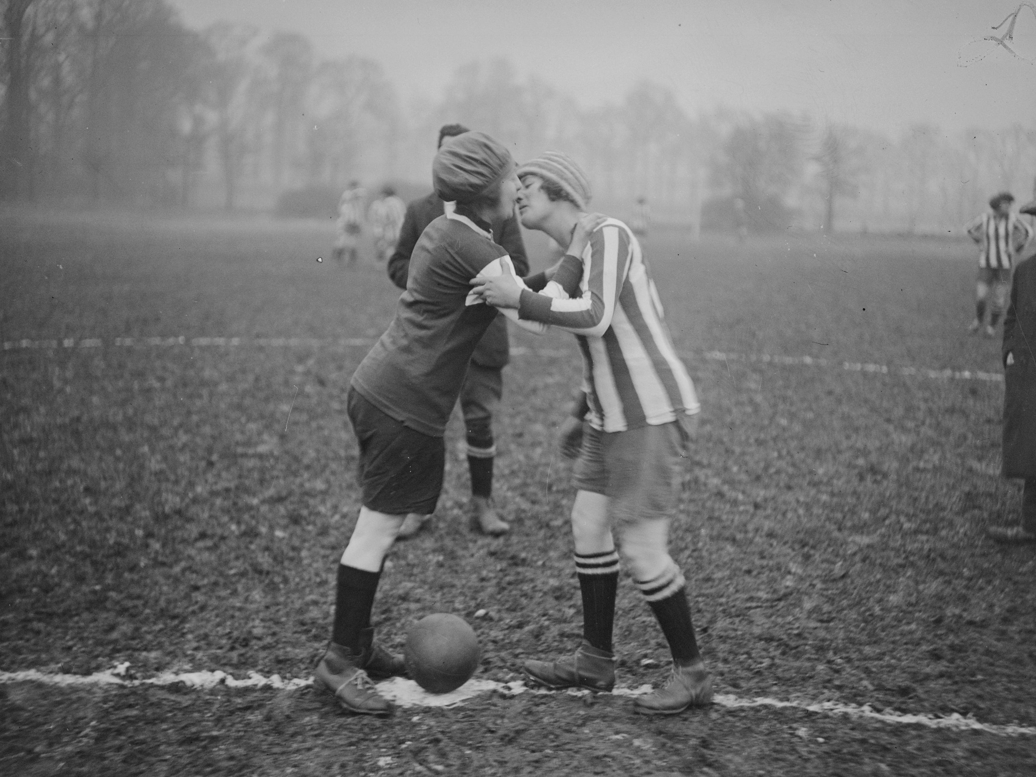 Two women kiss before a soccer match.