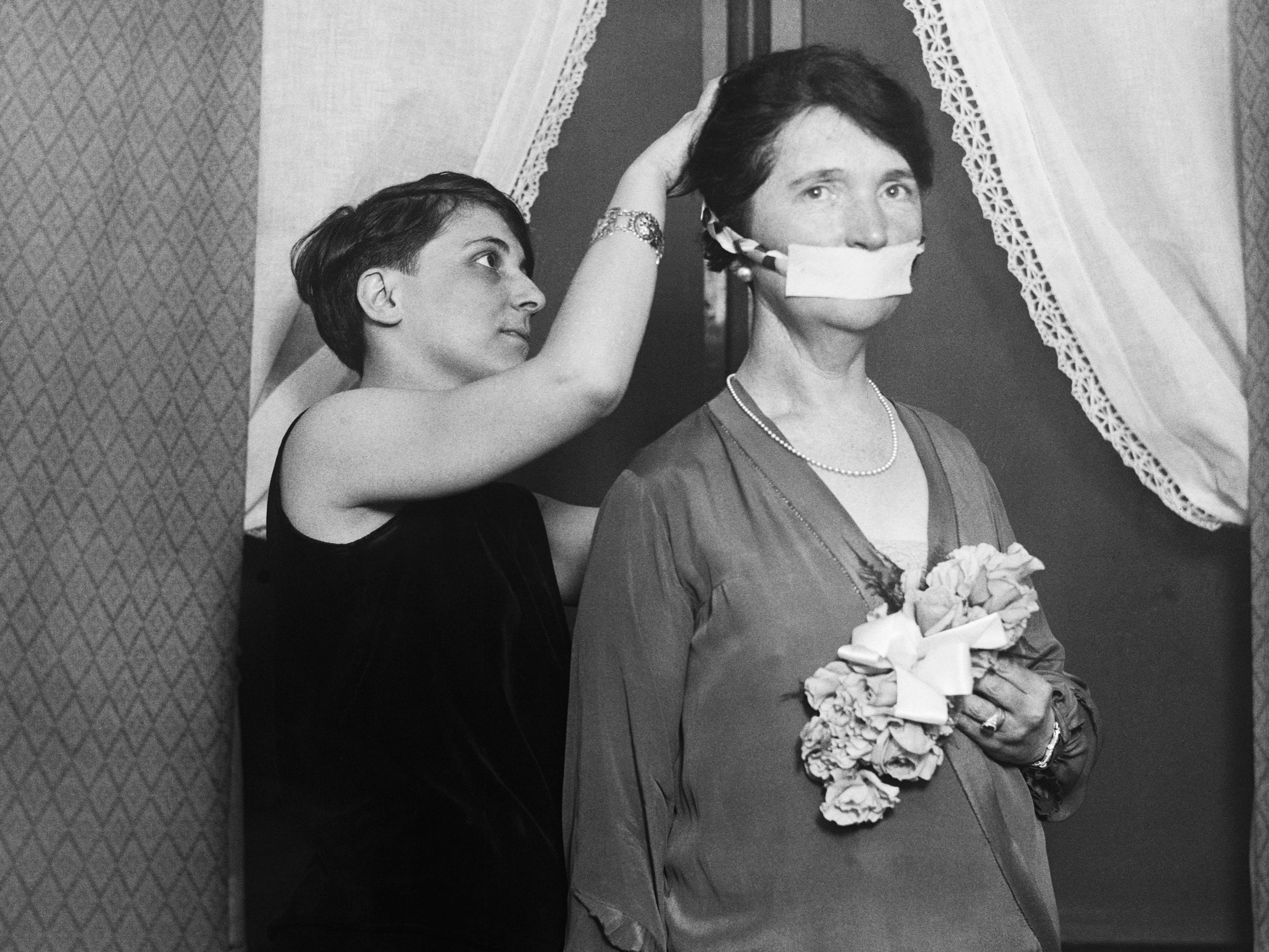 Margaret Sanger has her mouth covered, protesting not being able to talk about birth control in Boston.