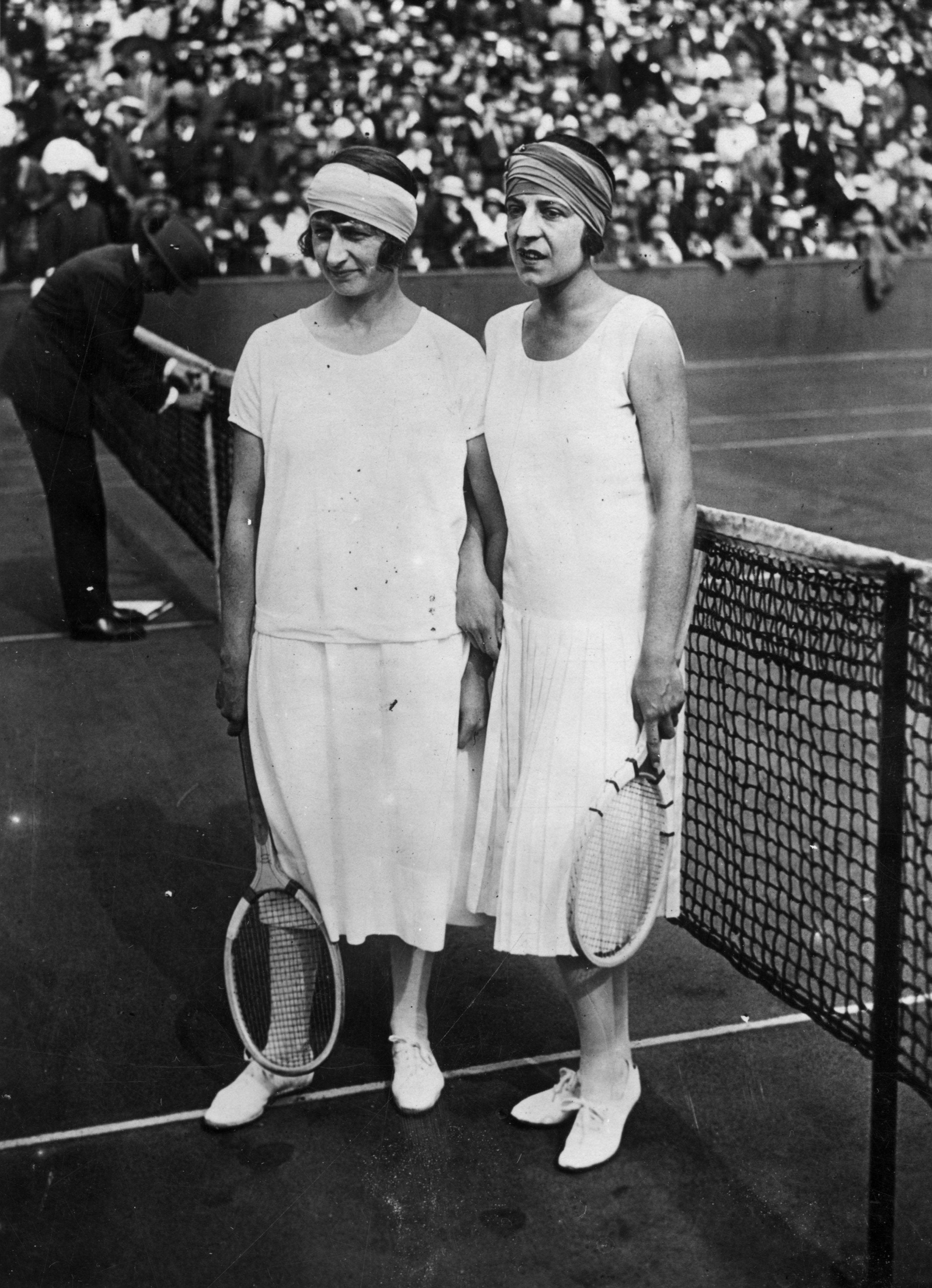 Kitty McKane and Suzanne Lenglen posed together after their women's singles final at the French National Hard Court Championships in 1925. They wore loose-fitting white shirts and long white skirts to compete. They also each wore thick headbands.