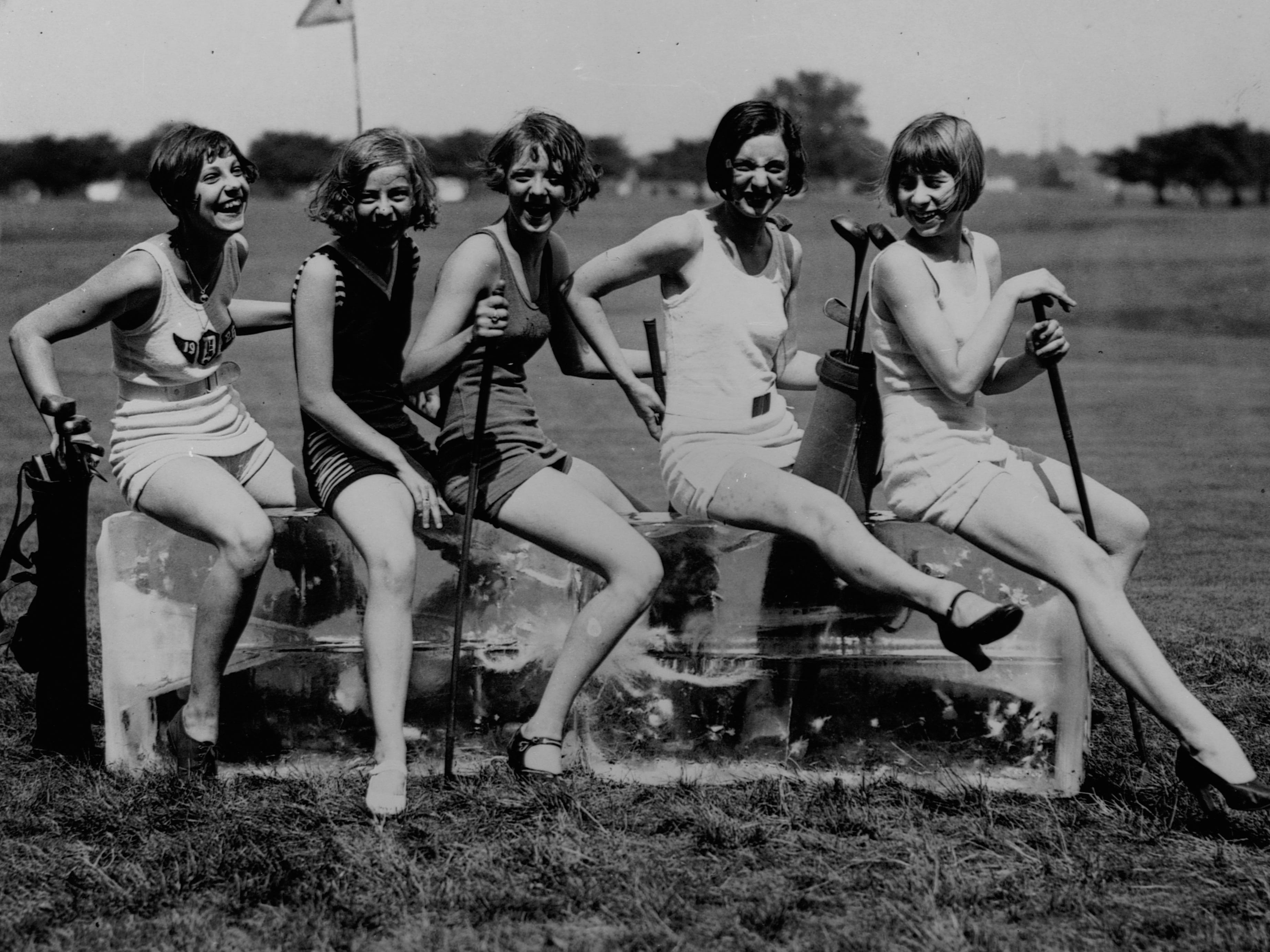 Dorothy Kelly, Virginia Hunter, Elaine Griggs, Hazel Brown, and Mary Ka Minsky laughing and sitting on a large block of ice on a golf course in 1920.