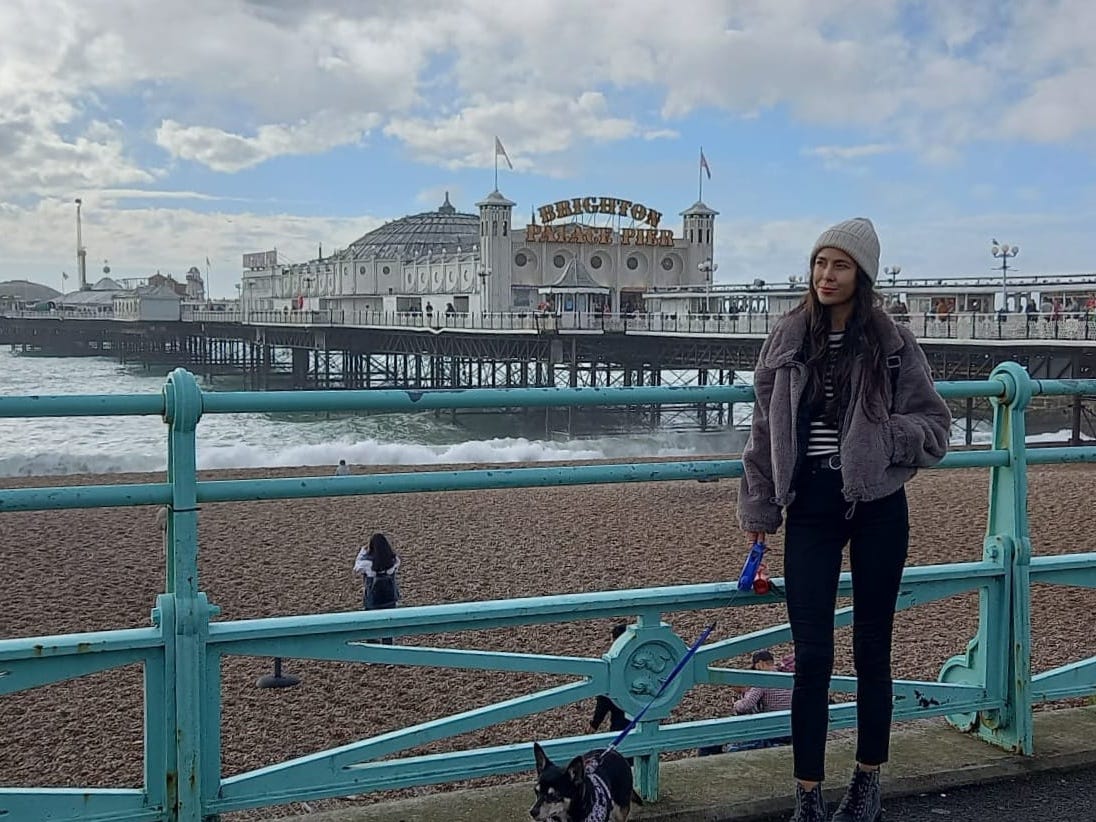 A woman and her dog stand in front of a pier in Brighton, England.