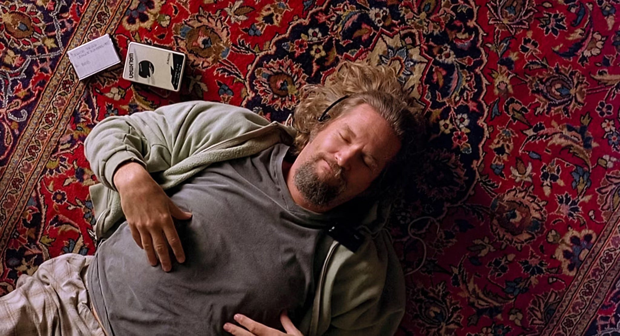 Jeff Bridges laying on a carpet listening to music on headphones