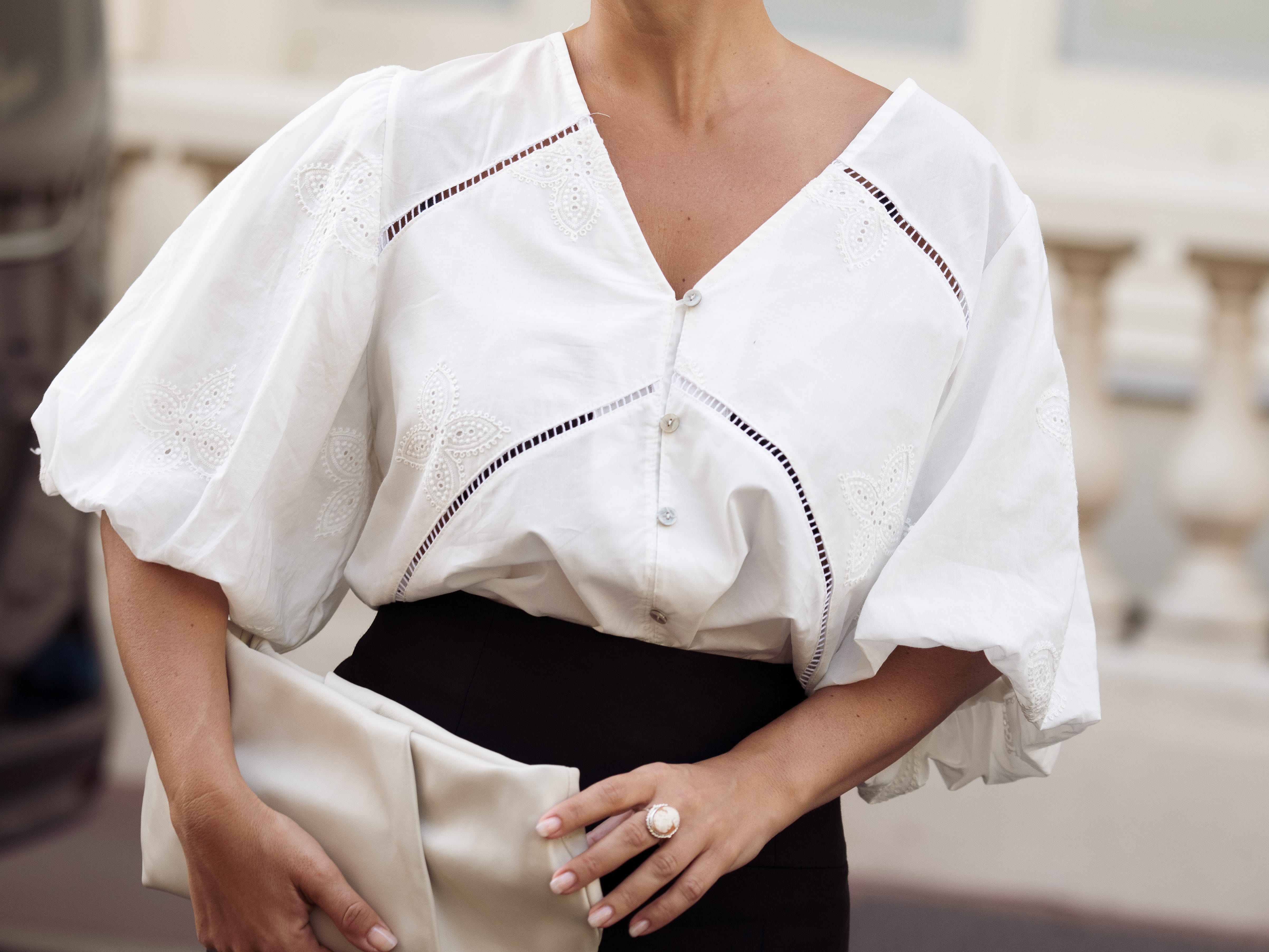 A woman wearing a white blouse with billowy sleeves.