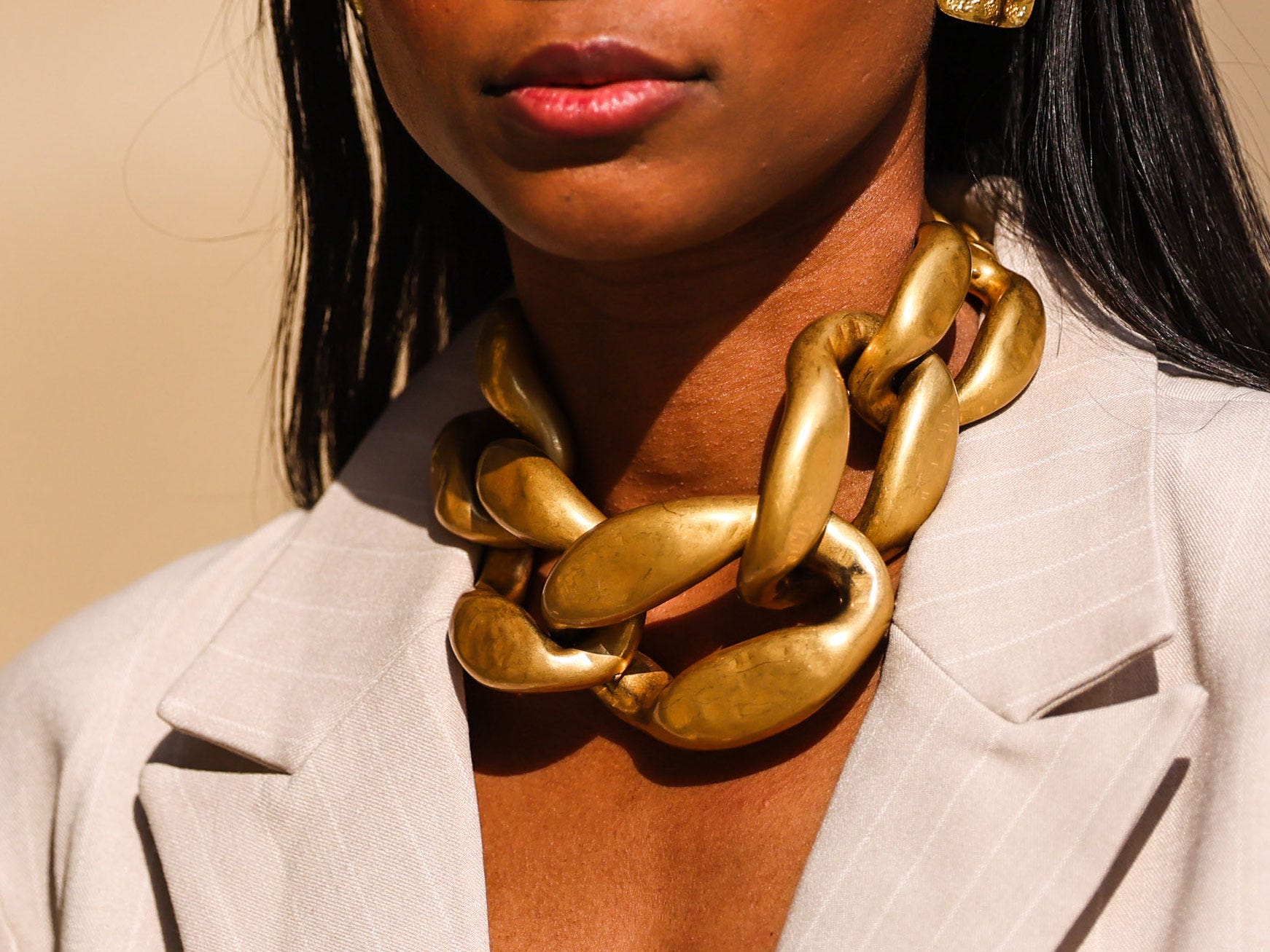 A woman wearing a chunky gold statement necklace.