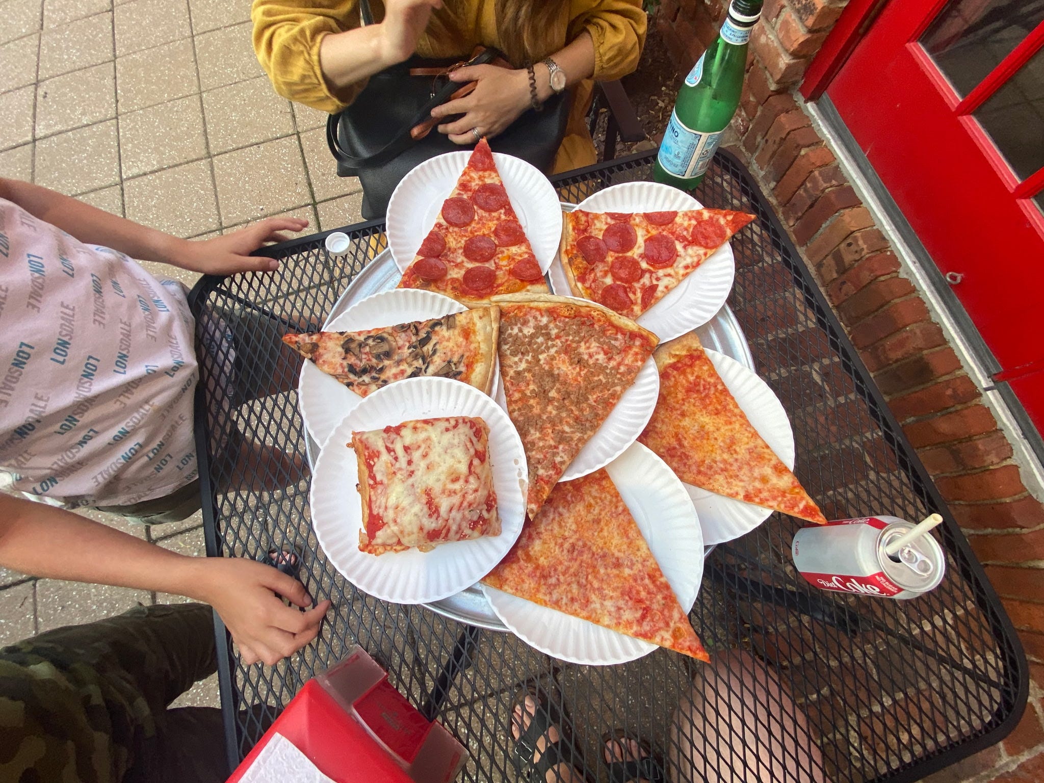 Metal table in NYC covered in paper plates of pizza