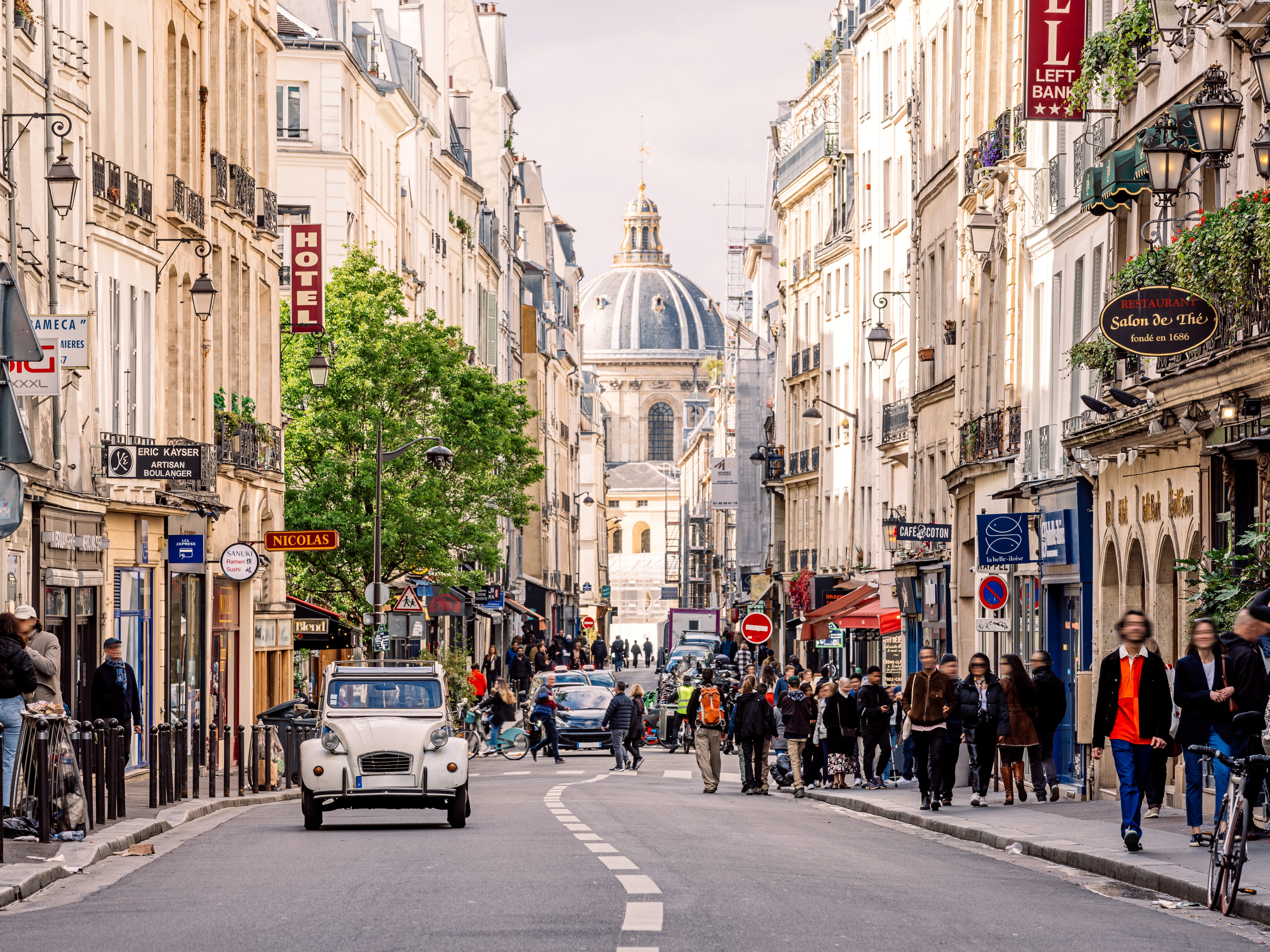 A crowded street with cafés and restaurants in Paris.