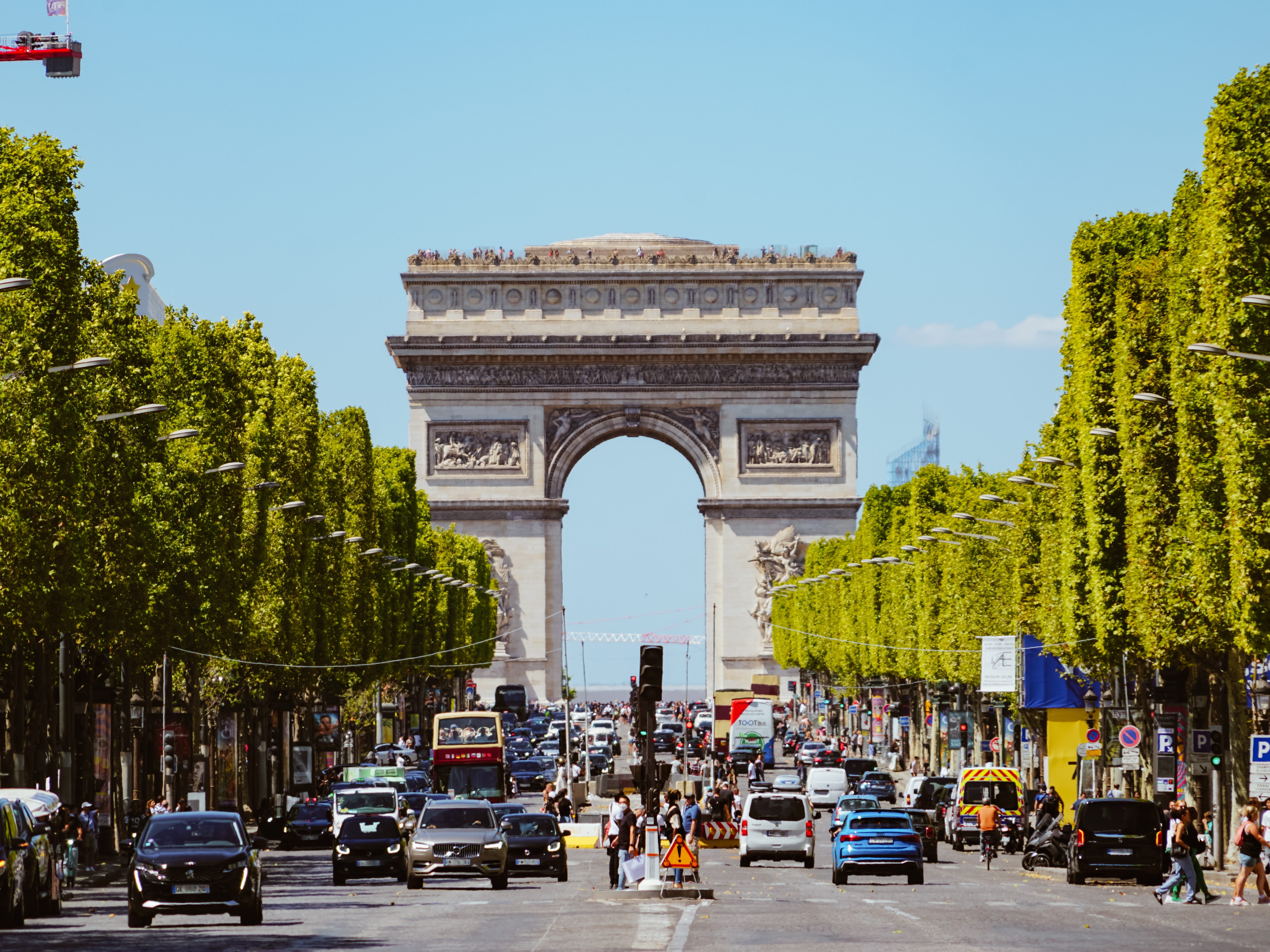 Rows of trees line a busy street at the Arc de Triomphe.