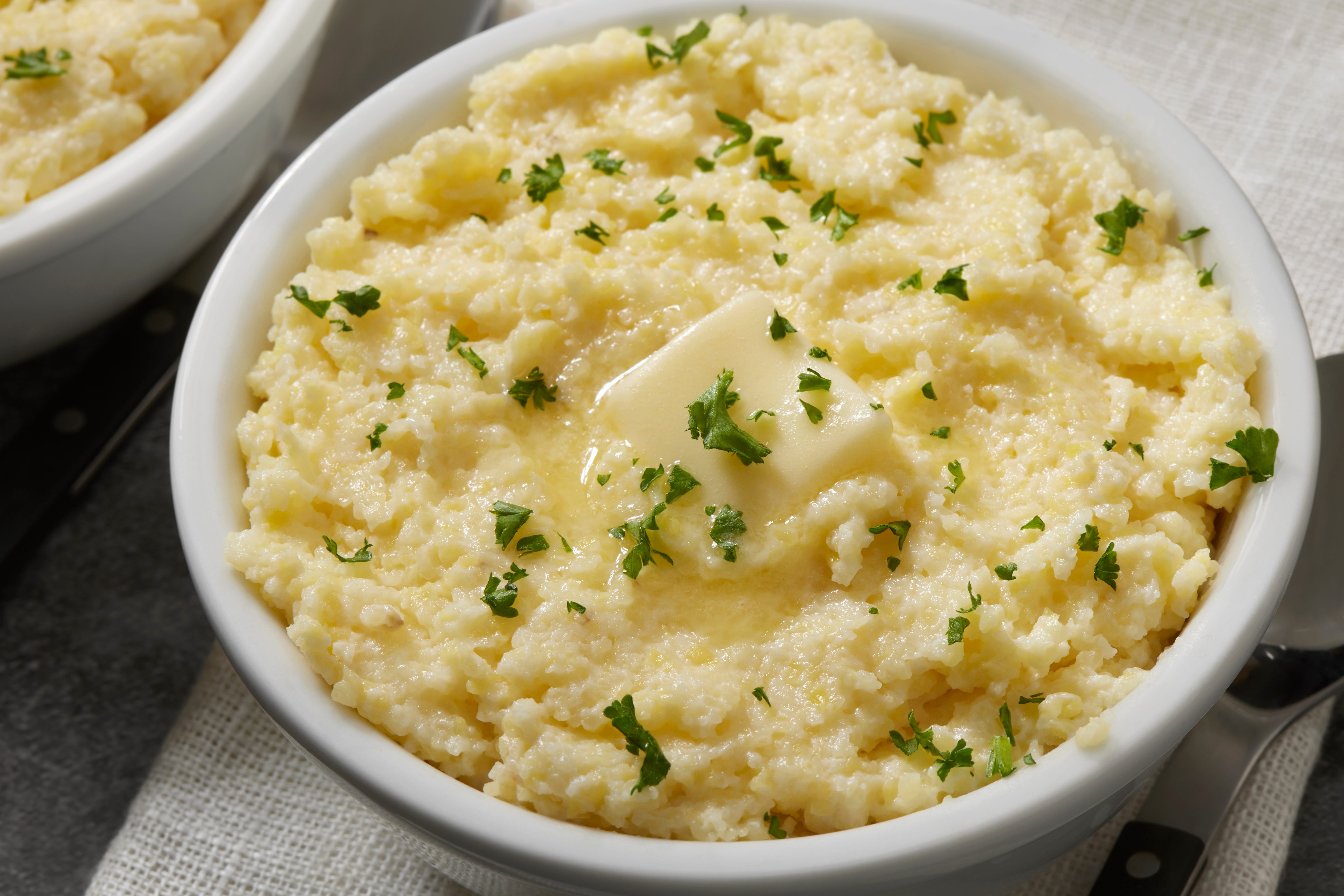 Bowl of mashed potatoes topped with pat of butter and herbs