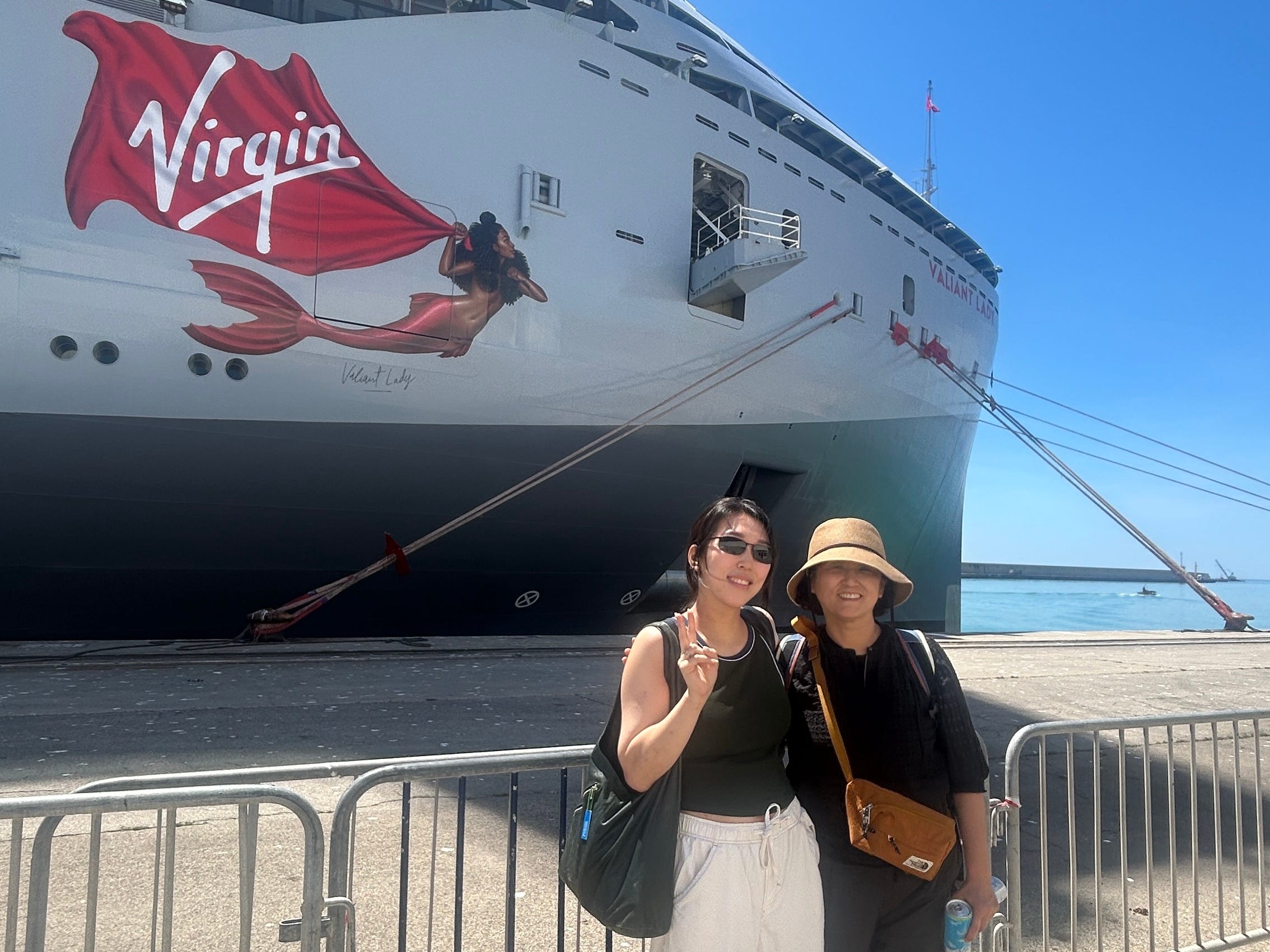 The writer and her mom posing in front of a Virgin Voyages cruise ship.