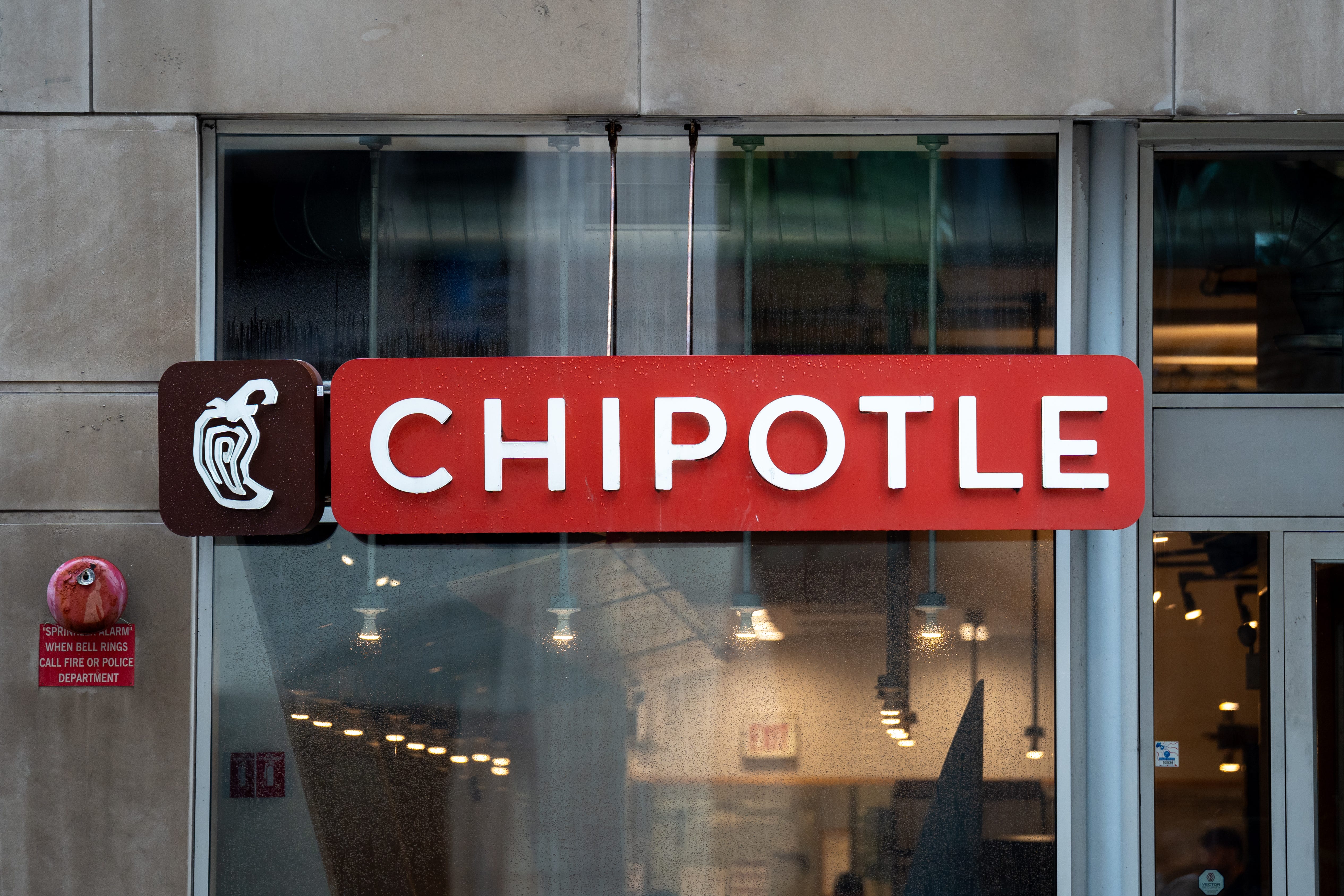 Chipotle storefront sign with white lettering on a red panel above glass windows.
