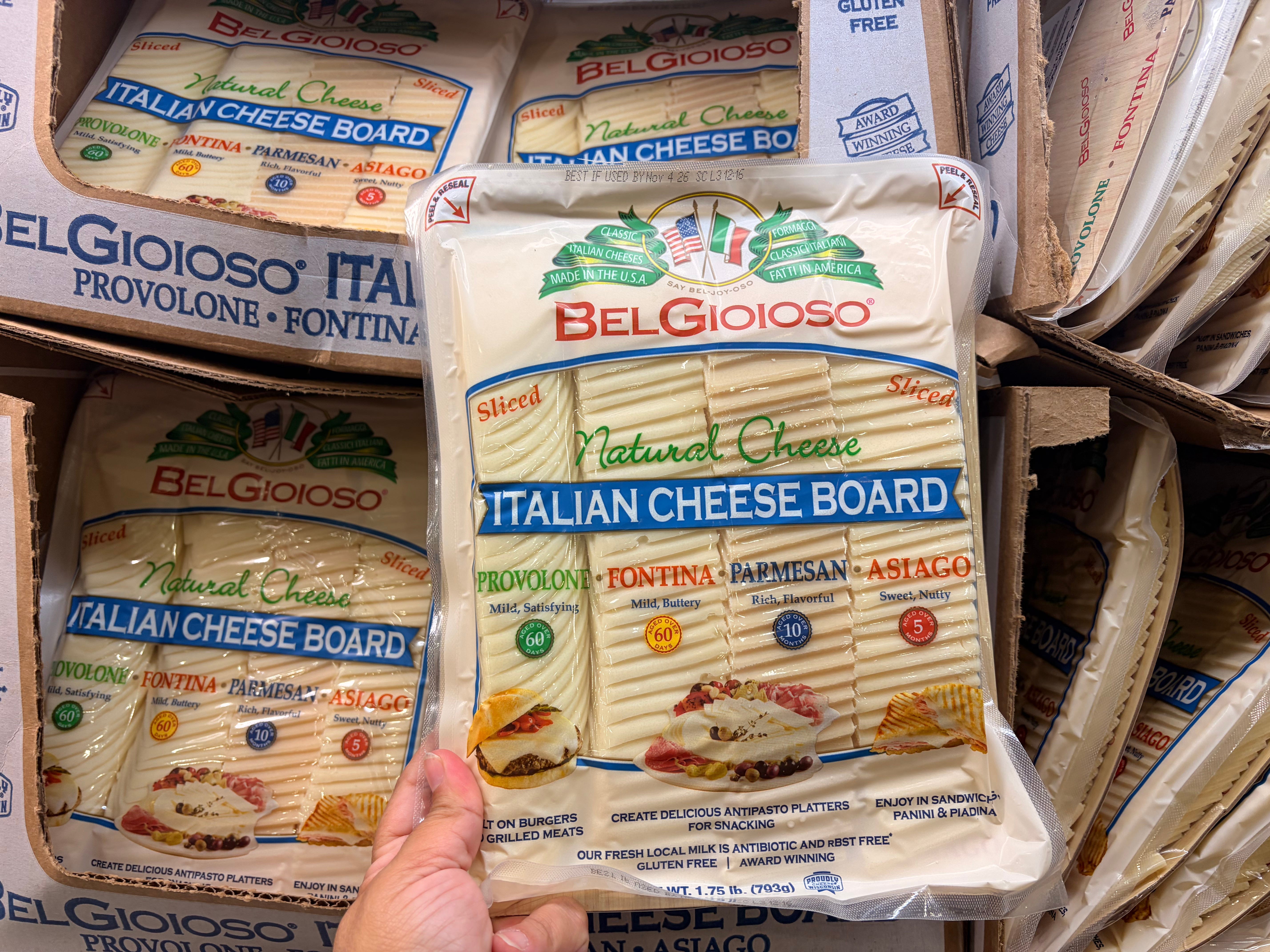 A hand holding a multipack of BelGioioso cheeses.