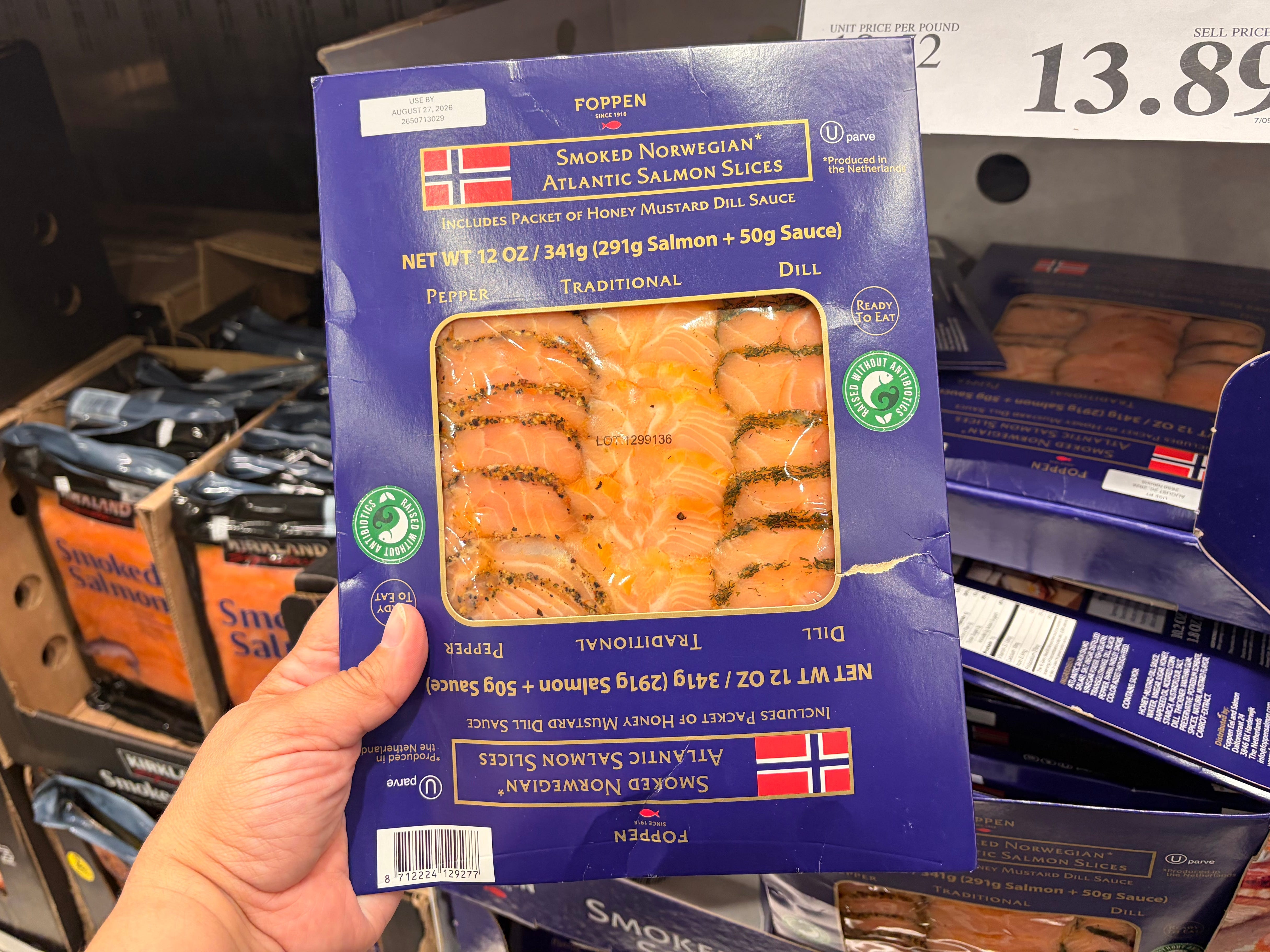 A hand holding a container of Poppen smoked Norwegian Atlantic salmon slices.